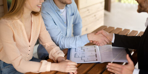 Couple shaking hands with seller after property settlement