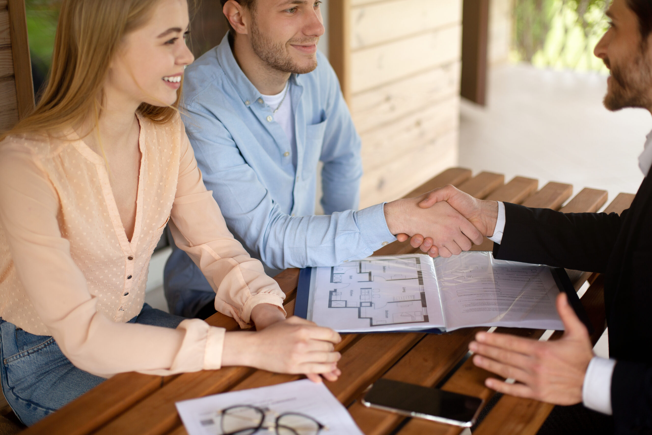 Couple shaking hands with seller after property settlement
